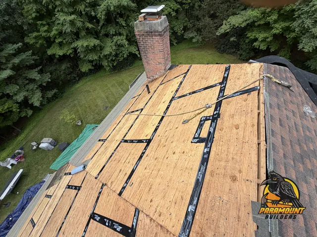 Exposed roof decking with taped seams beside brick chimney - Exterior work, home in progress, Avon, CT